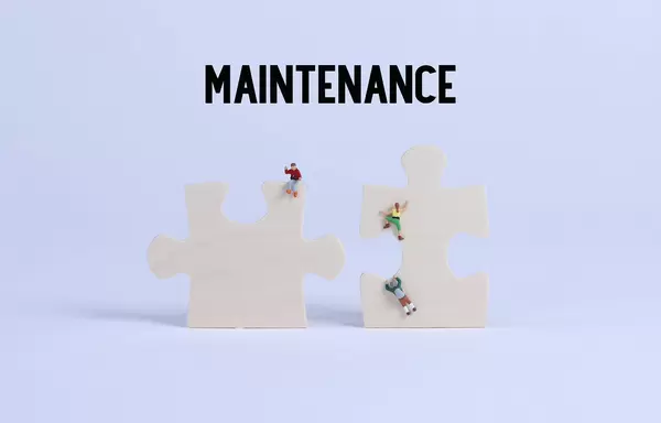 Miniature climbers on puzzle pieces with Maintenance text