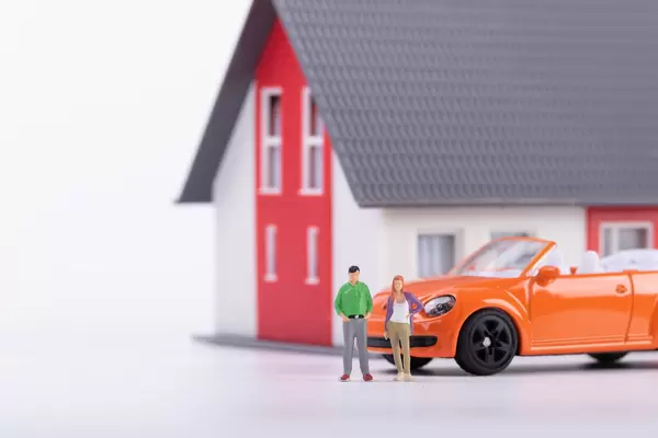 Miniature couple with orange car and a house