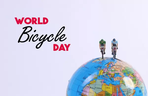 Miniature Figures Ride Bicycle on globe and World Bicycle Day text