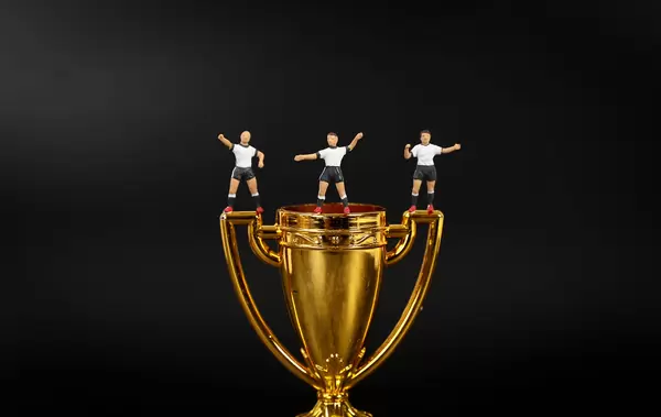 Miniature football players with golden trophy
