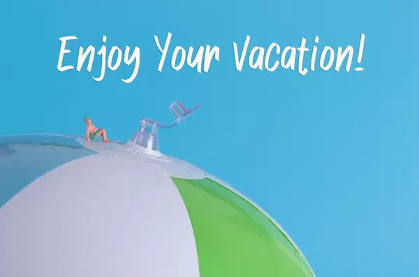 Miniature man in swimsuit sitting on a beach ball with Enjoy Your Vacation text