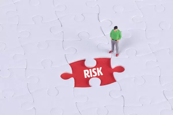 Miniature man looking at a missing puzzle piece with Risk text