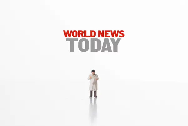 Miniature man reading newspaper and World News Today text