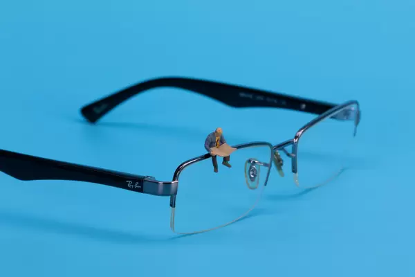 Miniature man sitting and reading on glasses