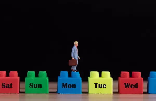 Miniature man walking on plastic building blocks