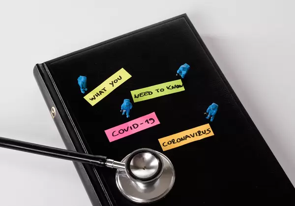Miniature medical workers dressed in protective suits and stethoscope on black notebook