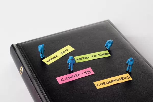 Miniature medical workers dressed in protective suits on black notebook