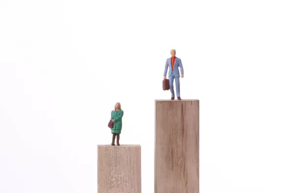 Miniature men and women standing on the different height block