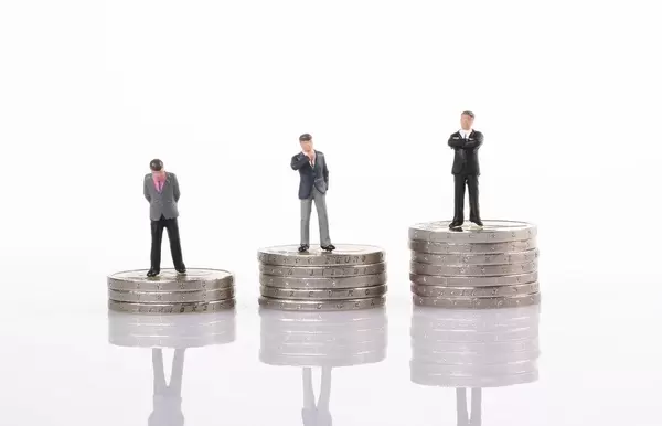 Miniature model of businessman standing on coin stacks