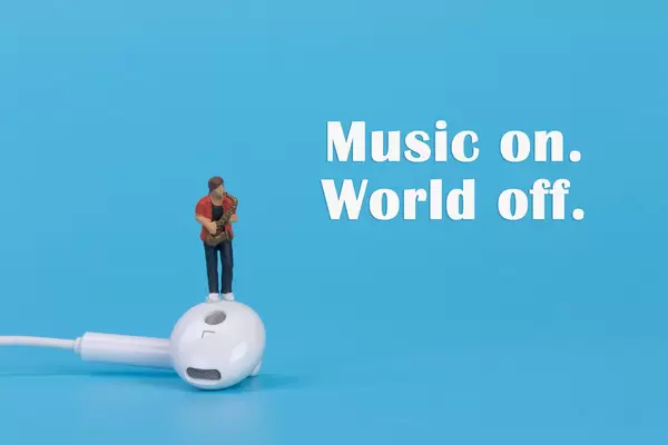 Miniature musician with earbud and Music on World off text