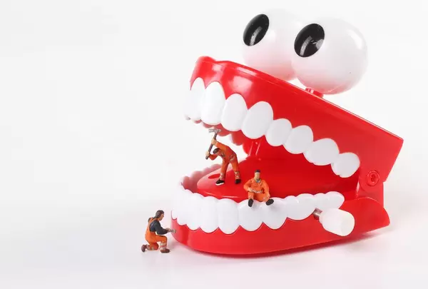 Miniature people cleaning teeth on white backgroudn