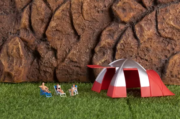 Miniature people relaxing in deckchairs in the nature