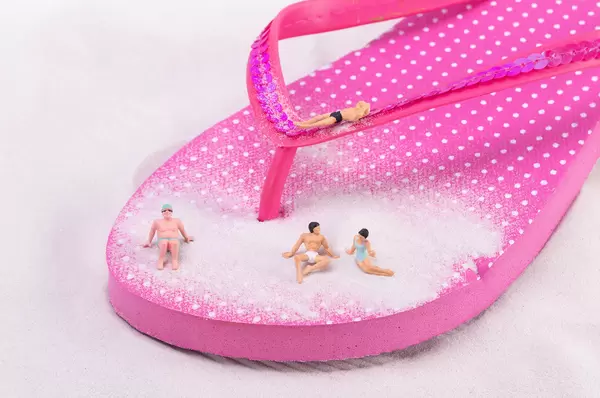 Miniature people relaxing on flip flops shoe
