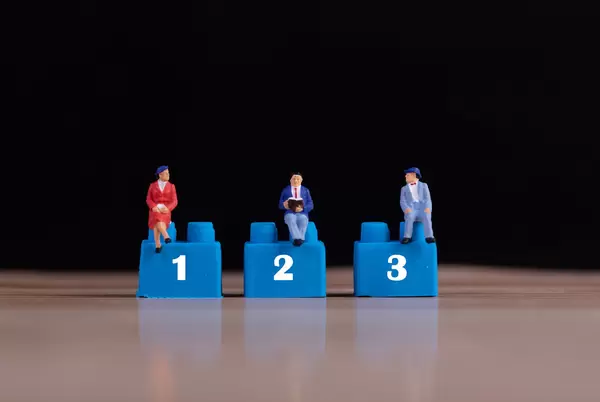 Miniature people sitting on plastic building blocks