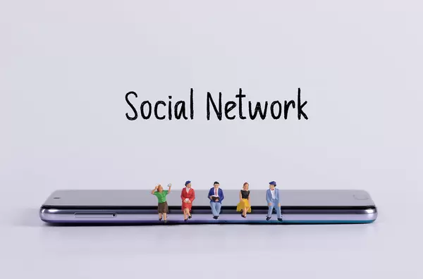 Miniature people sitting on smartphone with Social Network text