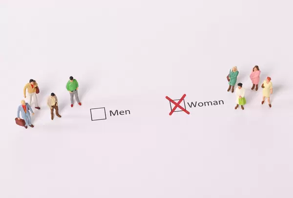 Miniature people standing in front of a check box selected as a Woman