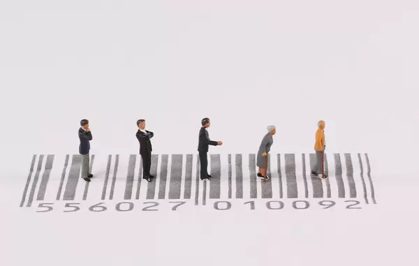 Miniature people standing on bar code