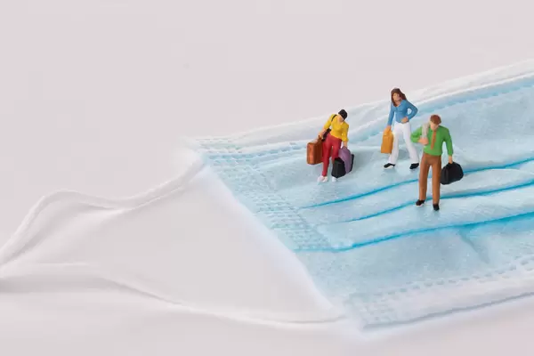 Miniature people standing on medical face mask