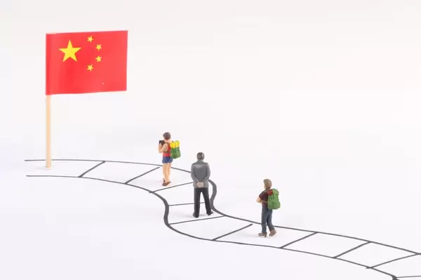 Miniature people walking on a path to the flag of China