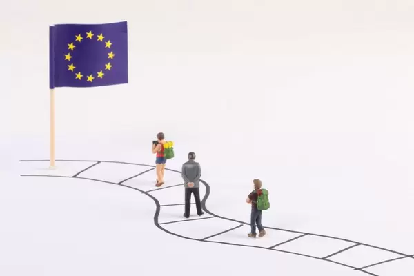 Miniature people walking on a path to the flag of European Union