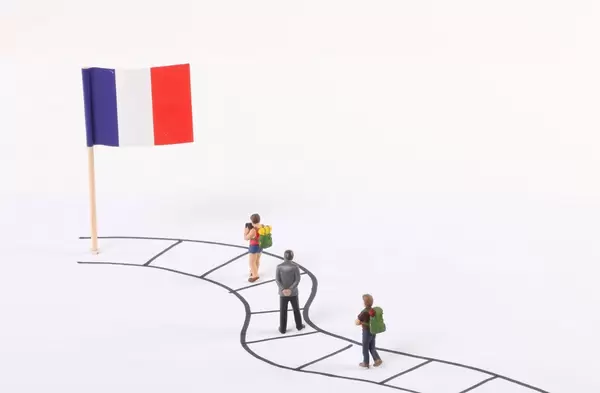Miniature people walking on a path to the flag of France