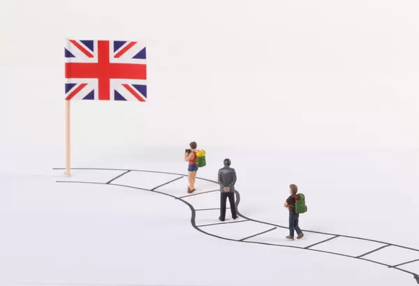 Miniature people walking on a path to the flag of United Kingdom