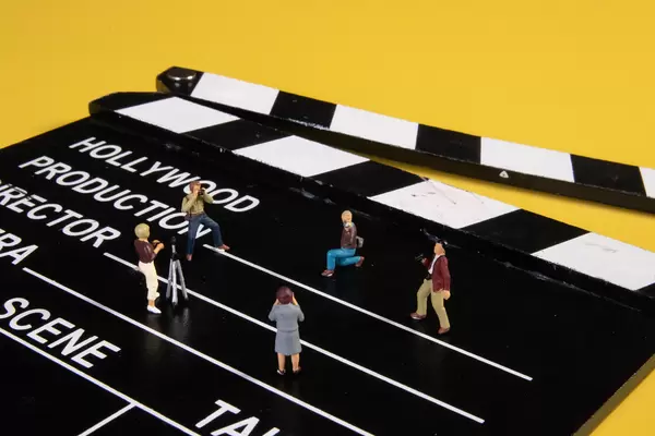 Miniature people with cameras on movie clapper