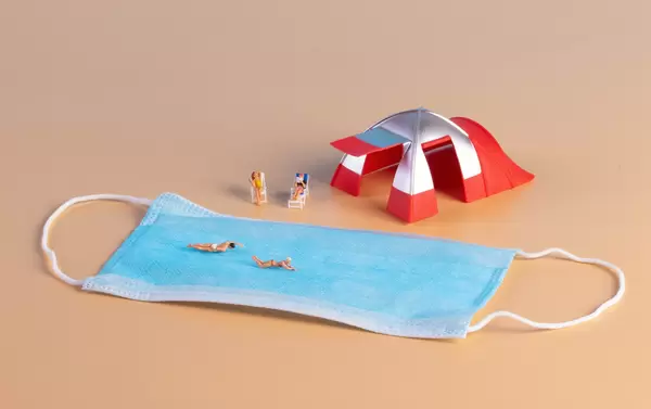 Miniature people with camping tent and medical face mask