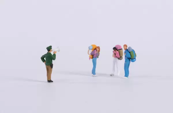 Miniature policeman with group of backpackers on white