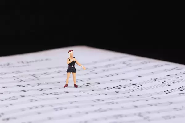 Miniature singer standing on music notes