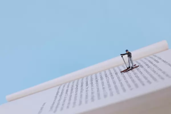 Miniature skier skiing on book