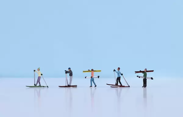 Miniature skiers on light blue background