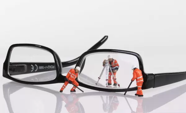 Miniature technician repairing reading glasses. Business concept