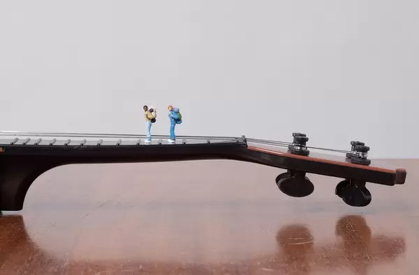 Miniature travelers on a guitar