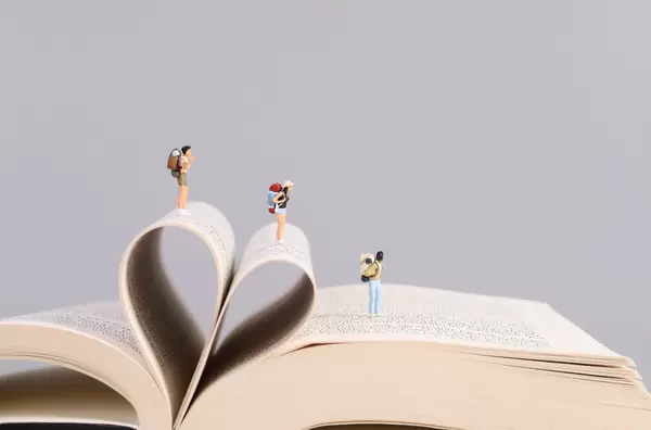 Miniature travelers on opened book and heart shape