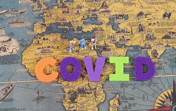 Miniature travelers on the map with Covid text