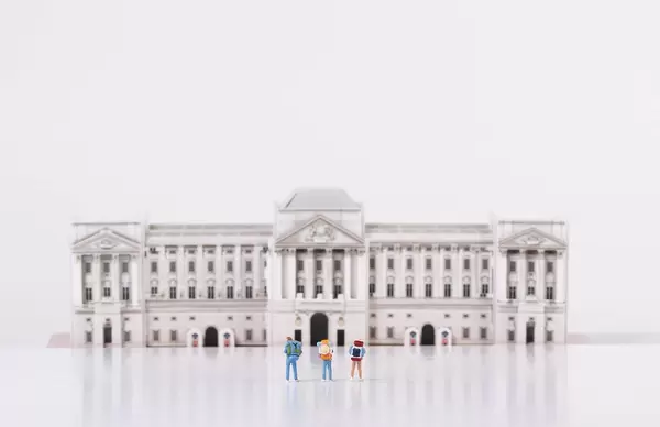 Miniature travelers stading in front of Buckingham Palace