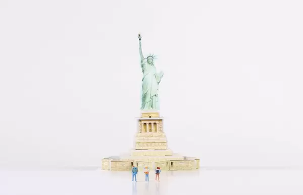 Miniature travelers stading in front of Statue of Liberty