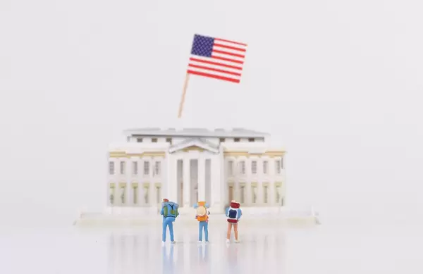 Miniature travelers stading in front of the White House with USA flag