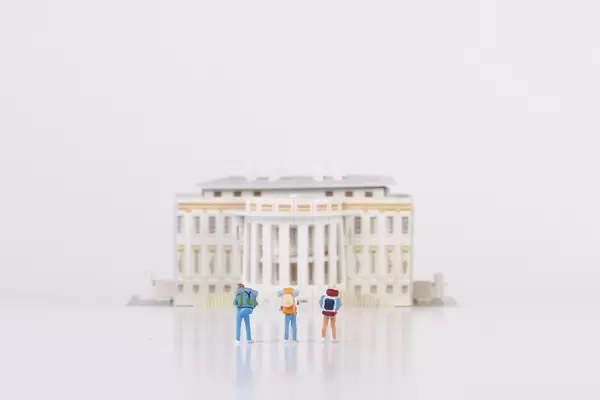 Miniature travelers stading in front of the White House