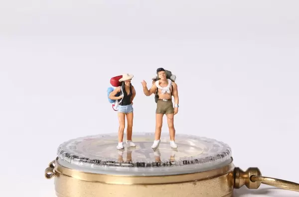 Miniature travelers standing on compas