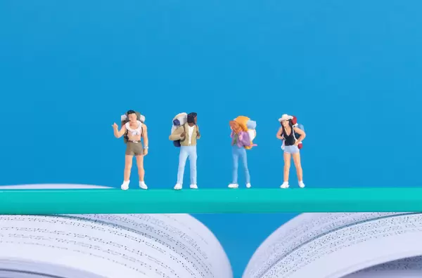 Miniature travelers standing on green pencil