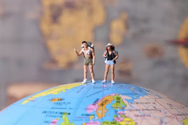 Miniature travelers standing on the globe with map in the background