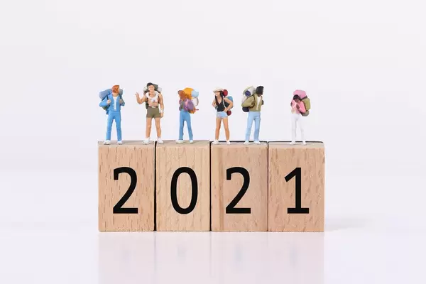 Miniature travelers standing on wooden blocks with 2021 text