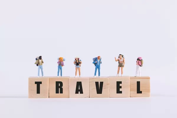 Miniature travelers standing on wooden cubes with Travel text