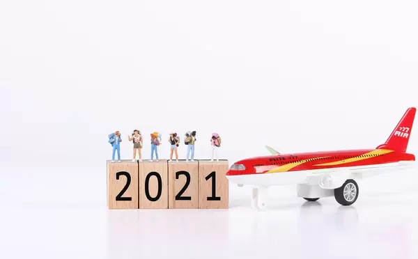Miniature travelers with airplane and wooden blocks with 2021 text