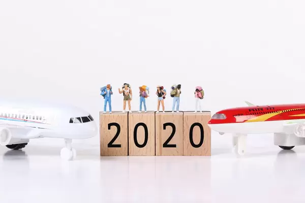 Miniature travelers with toy airplanes and 2020 text