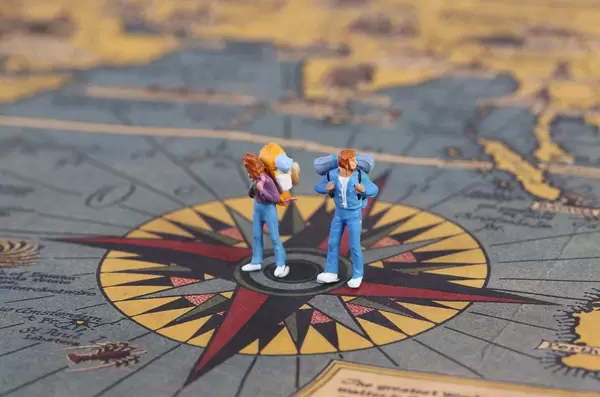Miniature travlers standing on the compas on map