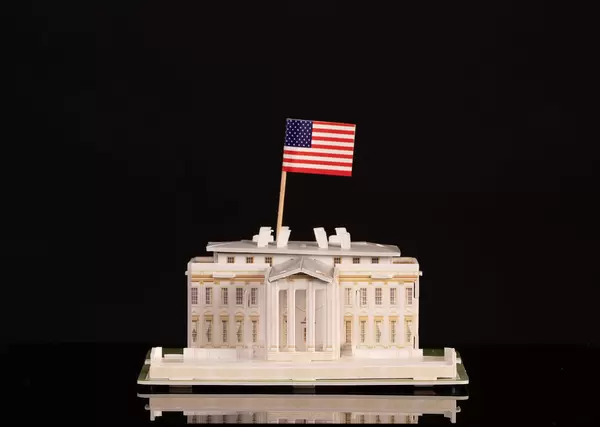 Miniature White House with American flag on black background