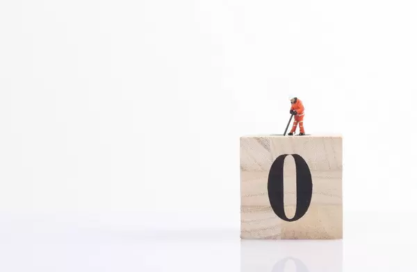 Miniature worker on wooden cube with big zero
